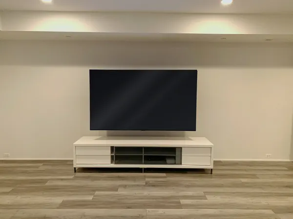 Large TV wall-mounted above media console in finished basement